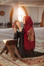 Young muslim woman praying in mosque with quran