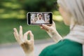 Young muslim woman, resting at park with digital smart phone, having a video call with her friend Royalty Free Stock Photo