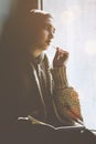 Young Muslim woman sits on the window sill. Middle-eastern writer woman sitting thoughtfully near the window and writing her story