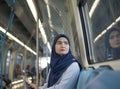 Young Muslim woman traveling inside subway train sitting looking at window. Royalty Free Stock Photo