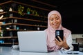 Young muslim woman using cellphone working on laptop in office Royalty Free Stock Photo