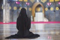 Young muslim woman in wear black dress sitting alone in mosque.