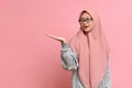 Young Muslim woman wearing casual clothes and glasses smiling cheerful presenting something with palm of hand Royalty Free Stock Photo