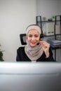 Young muslim women wearing hijab telemarketing or call center agent with headset working on support hotline at office Royalty Free Stock Photo