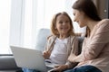 Young nanny and preteen girl watch education channel on laptop Royalty Free Stock Photo