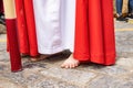 A young Nazarene or penitent with white and red clothes is doing his penance station with bare feet in the Holy Week procession Royalty Free Stock Photo