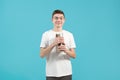 Young nerd guy with glasses naively smiles and holds books in his hands