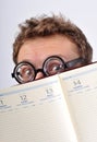 Young nerd hiding behind agenda Royalty Free Stock Photo