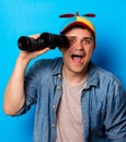 Young nerd man with noob hat using a binoculars