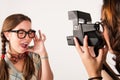 Young nerdy girls using instant camera.