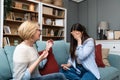 Young nervous overjoyed woman holding a pregnancy test tells her mom that she is pregnant and will have a baby. Future grandmother