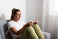 Young nervous woman is sitting at home holding a pregnancy test and is impatiently waiting for the test result. Maybe pregnant Royalty Free Stock Photo