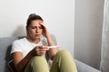 Young nervous woman is sitting at home holding a pregnancy test and is impatiently waiting for the test result. Maybe pregnant Royalty Free Stock Photo