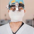 Young neurosurgeon man in a medical mask with professional magnifying glasses with binary loupes for microsurgery. Royalty Free Stock Photo