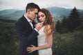 Young newly wed couple, bride and groom kissing, hugging on perfect view of mountains, blue sky Royalty Free Stock Photo