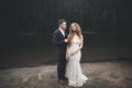 Young newly wed couple, bride and groom kissing, hugging on perfect view of mountains, blue sky Royalty Free Stock Photo