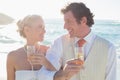 Young newlyweds having champagne linking arms