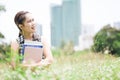 Young nice attentive woman sitting on green grass and hug book