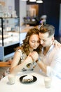 Young nice couple sitting at cafe with cups of coffe, cake and hugging. Royalty Free Stock Photo