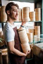 Cute Caucasian waiter is carrying stack of wooden dishes in the cafe