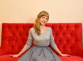 The young nice woman sits on a red sofa Royalty Free Stock Photo