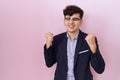 Young non binary man with beard wearing suit and tie very happy and excited doing winner gesture with arms raised, smiling and Royalty Free Stock Photo