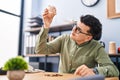 Young non binary man business worker emptying piggy bank at office