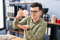 Young non binary man business worker emptying piggy bank at office