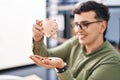 Young non binary man business worker emptying piggy bank at office