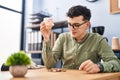 Young non binary man business worker emptying piggy bank at office