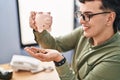 Young non binary man business worker emptying piggy bank at office