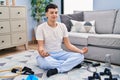 Young non binary man doing yoga exercise sitting on floor at home