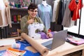 Young non binary man dressmaker designer on video call with laptop smiling happy pointing with hand and finger Royalty Free Stock Photo