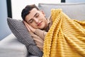 Young non binary man lying on sofa sleeping at home