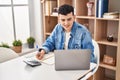 Young non binary man sitting on table doing the accounting at home