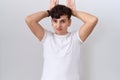 Young non binary man wearing casual white t shirt doing bunny ears gesture with hands palms looking cynical and skeptical