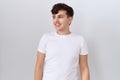 Young non binary man wearing casual white t shirt looking away to side with smile on face, natural expression Royalty Free Stock Photo