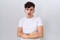 Young non binary man wearing casual white t shirt in shock face, looking skeptical and sarcastic, surprised with open mouth