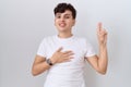 Young non binary man wearing casual white t shirt smiling swearing with hand on chest and fingers up, making a loyalty promise Royalty Free Stock Photo