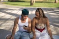Young, non-conformist Latino and Hispanic boy and girl couple sitting on a bench checking social networks on their cell phone.
