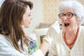 Young nurse or doctor checking the sore throat of a senior patient at home. Royalty Free Stock Photo