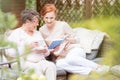 Young nurse and an elderly woman reading a book together on the Royalty Free Stock Photo