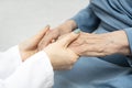 Young nurse hands holding an old hands of senior woman.