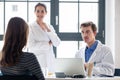 Young nurse listening to an experienced physician while consulting a patient