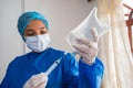 Young nurse with mask and hands in gloves preparing saline solution, holding a syringe with saline solution for patient hydration Royalty Free Stock Photo