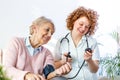 Young nurse measuring blood pressure of elderly woman at home. Female nurse checking blood pressure of a senior woman at home,Home