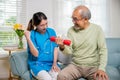 Young nurse physiotherapist helping old man in lifting dumbell at home Royalty Free Stock Photo