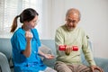 Young nurse physiotherapist helping old man in lifting dumbell at home Royalty Free Stock Photo