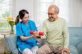 Young nurse physiotherapist helping old man in lifting dumbell at home Royalty Free Stock Photo