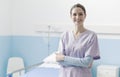 Young nurse posing next to a hospital bed